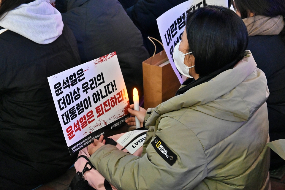 한 시민이 촛불과 함께 "윤석열 퇴진" 피켓을 들고 앉아 있다(2024.12.6) / 사진.평화뉴스 정준민 기자