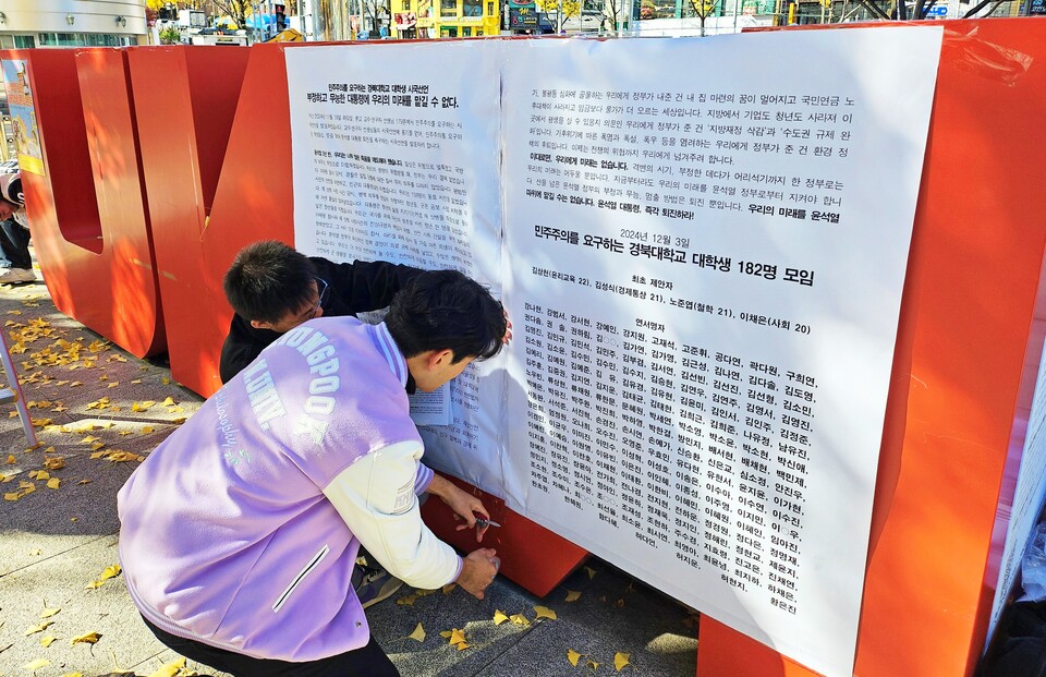 경북대 학생들이 시국선언을 발표한 뒤 경북대 북문 앞에 설치된 조형물에 시국선언문을 붙이고 있다(2024.12.3) / 사진.평화뉴스 정준민 기자