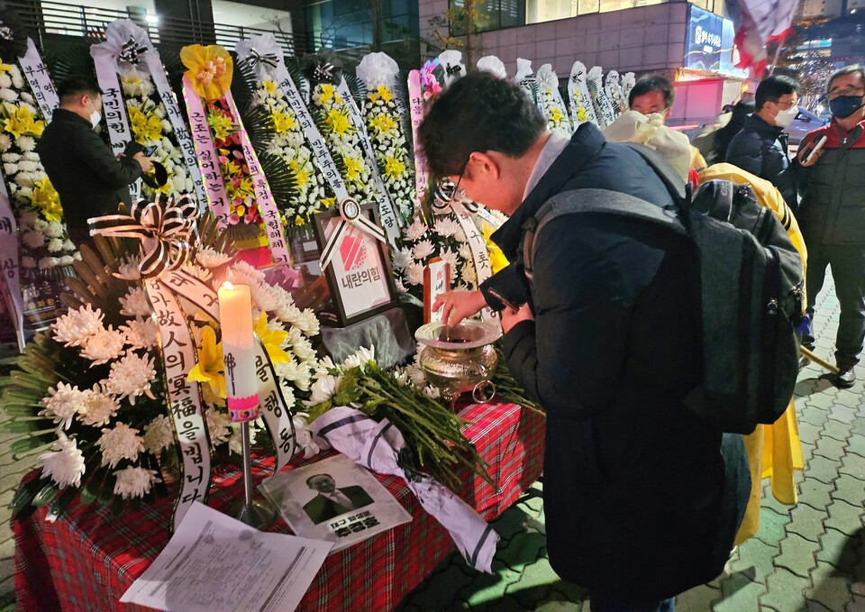 한 시민이 내란의힘 영정사진 앞에 향에 불을 붙혀 꽂고 있다.(2024.12.11) / 사진.평화뉴스 정준민 기자