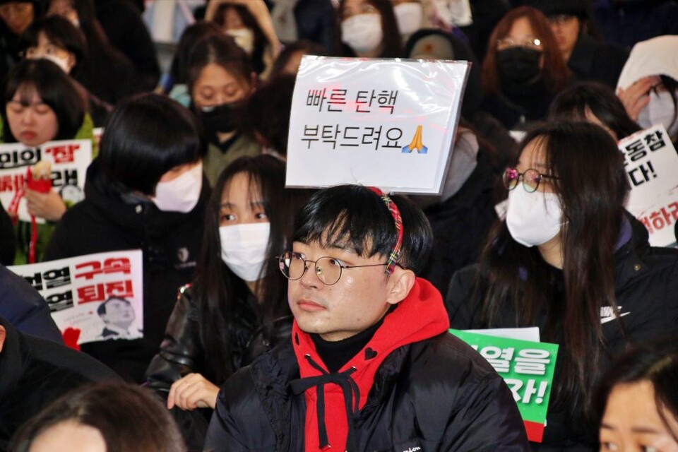 한 청년이 "빠른 탄핵 부탁드려요" 피켓을 머리띠로 만들어 쓰고 있다.(2024.12.13) / 사진.평화뉴스 김영화 기자