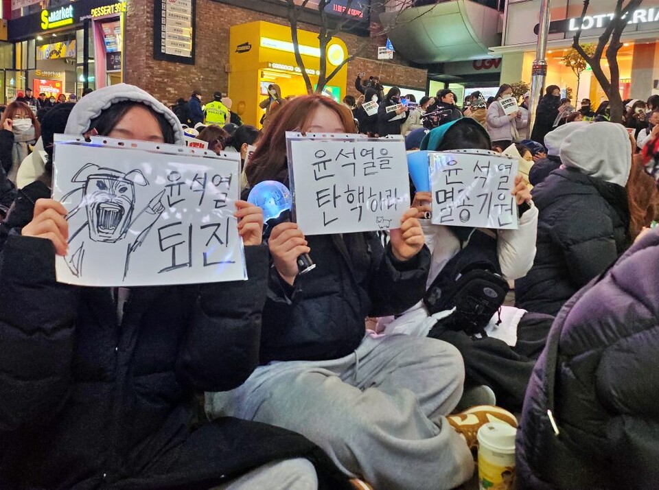 제5차 대구시국대회에서 20대 여성들이 '윤석열 퇴진', '윤석열 멸종기원', '윤석열 탄핵' 등 직접 만든 피켓과 함께 방탄소년단(BTS) 아미봉을 흔들고 있다.(2024.12.9) / 사진.평화뉴스 정준민 기자  