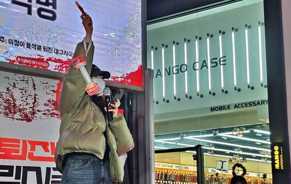 익명의 한 20대 여성이 자신이 좋아하는 한 아이돌팀의 응원봉과 LED 촛불을 들고 무대에 올라 "내란범 윤 대통령은 퇴진하라"고 규탄하는 자유발언을 하고 있다.(2024.12.9) / 사진.평화뉴스 정준민 기자