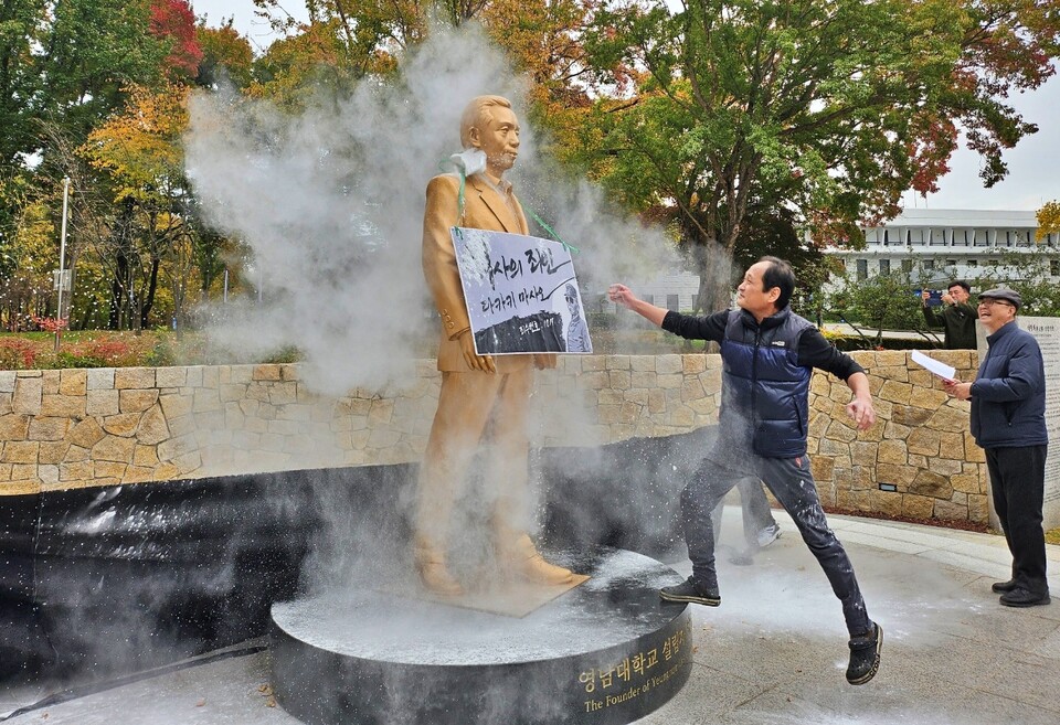 영남대 한 동문이 박정희 동상에 밀가루를 뿌리고 있다.(2024.11.10) / 사진.평화뉴스 정준민 기자