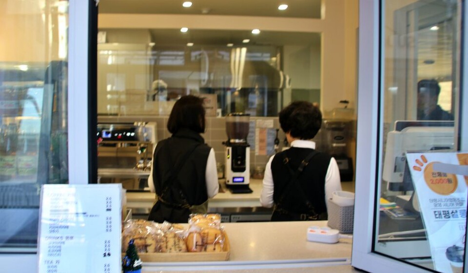 태평살롱 주문대인 창문 너머로 두 바리스타가 오순도순 이야기를 나누고 있다.(2024.12.31)  사진.평화뉴스 김영화 기자