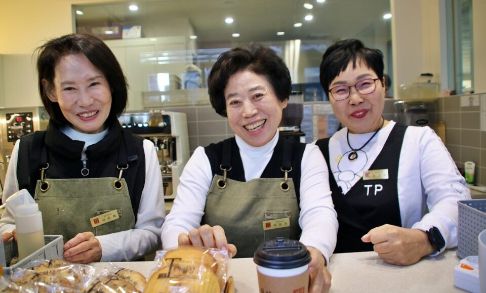 (왼쪽부터)서순재, 이미자, 윤성순 시니어 바리스타들이 손님에게 커피를 내주며 환하게 웃고 있다.(2024.12.31) / 사진.평화뉴스 김영화 기자