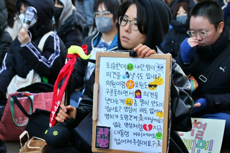 "죄송한데 내란범이 의견을 낼 수도 있나요?" 한 시민이 직접 가져온 보드판에 윤 대통령을 비판하는 풍자적 문구를 적었다.(2025.2.22) / 사진.평화뉴스 김영화 기자 