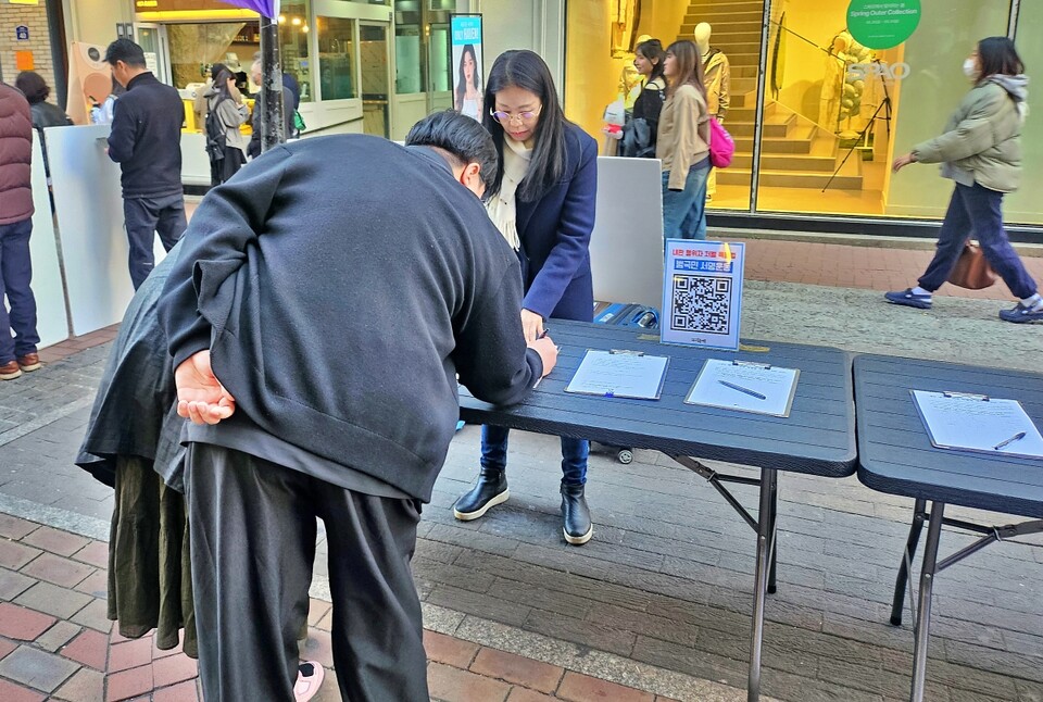 대구촛불행동의  '내란 행위자 처벌 특별법 제정' 서명운동에 한 시민이 서명하고 있다.(2025.3.10) / 사진.평화뉴스 정준민 기자