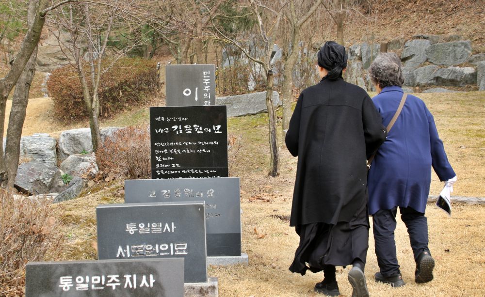 경기도 이천 민주화운동기념공원에서 손을 잡고 남편들 묘비로 가는 이정숙씨와 류승옥씨(2025.3.25) / 사진.평화뉴스 김영화 기자