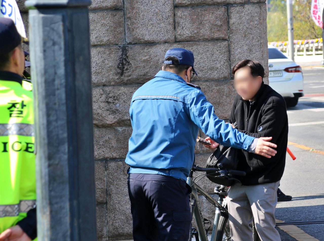 산격청사 정문 앞에서 자전거를 타고 지나가는 대구시민이 경찰에게 신분증을 제출하고 있다.(2025.4.11) / 사진.평화뉴스 김영화 기자