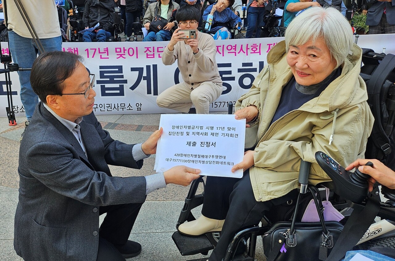 장관식 국가인권위 대구인권사무소장(왼쪽)이 박명애 상임공동대표로부터 진정서를 받고 있다.(2025.4.11) / 사진.평화뉴스 정준민 기자