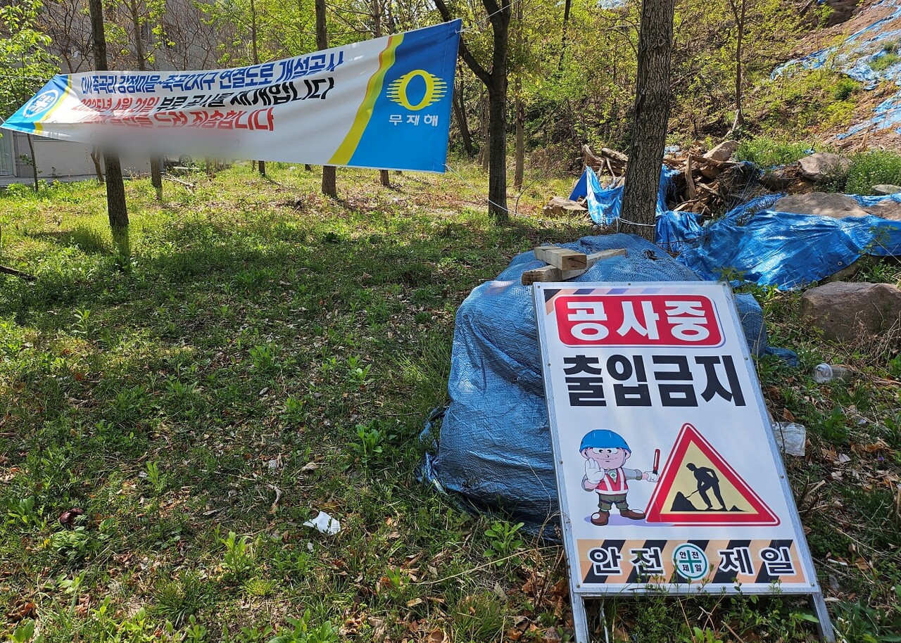 대구 달성군 죽곡산 도로 공사 현장 초입에 "공사중, 출입금지" 안내판과 "공사 재개" 현수막이 설치돼 있다.(2025.4.16) / 사진.평화뉴스 정준민 기자