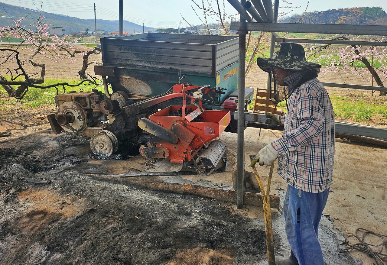 불에 타버린 농기계를 하염없이 지켜보는 농민 김동수(69)씨의 모습(2025.4.18) / 사진.평화뉴스 정준민 기자
