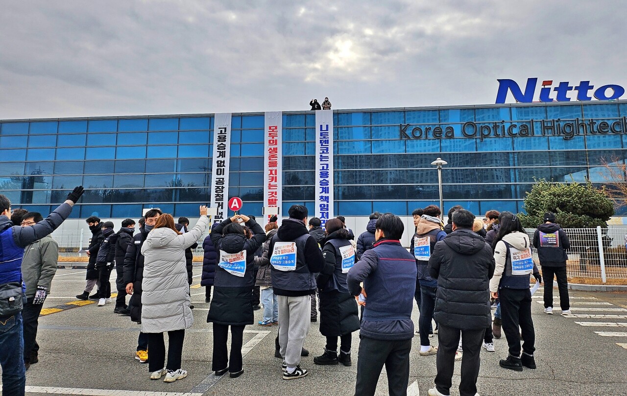 폐업한 경북 구미 한국옵티칼하이테크 공장 옥상에서 고공농성 중인 두 여성 해고자들을 향해 조합원들이 손을 흔들고 있다.(2024.1.9) / 사진.평화뉴스 정준민 기자