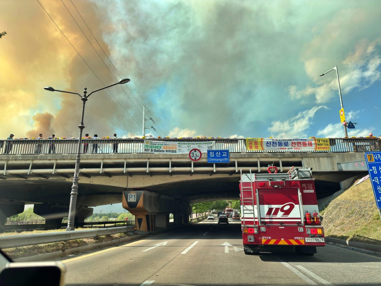 대구 북구 침산교 일대에서 산불을 지켜보는 주민들과  자욱한 연기. 119 소방차가 산불 현장으로 출동하고 있다.(2025.4.28) / 사진.독자 신원호 제공