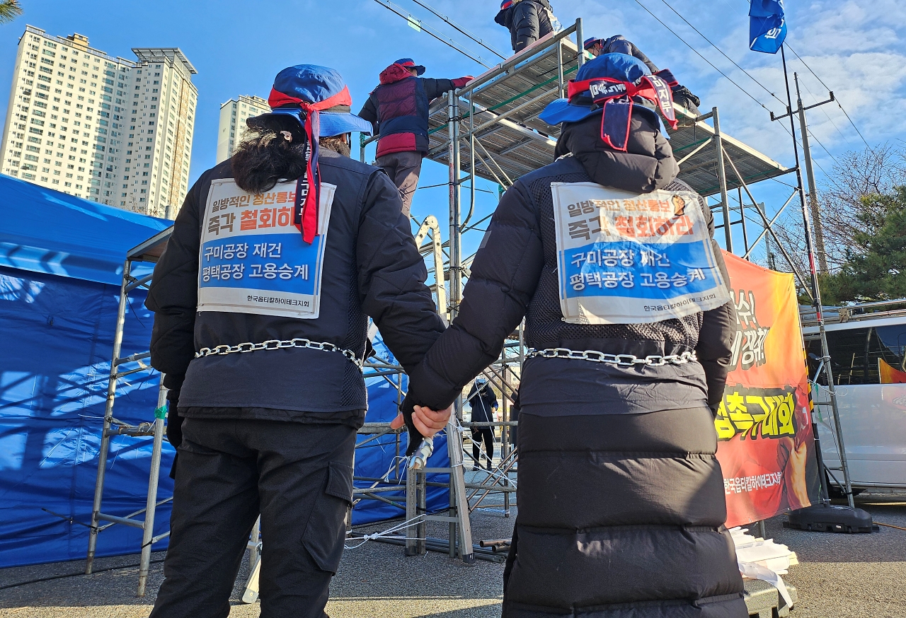 쇠사슬을 감은 경북 구미 한국옵티칼 해고노동자들이 망루 위 다른 해고자들을 보고 있다.(2024.2.16) / 사진.평화뉴스 정준민 기자