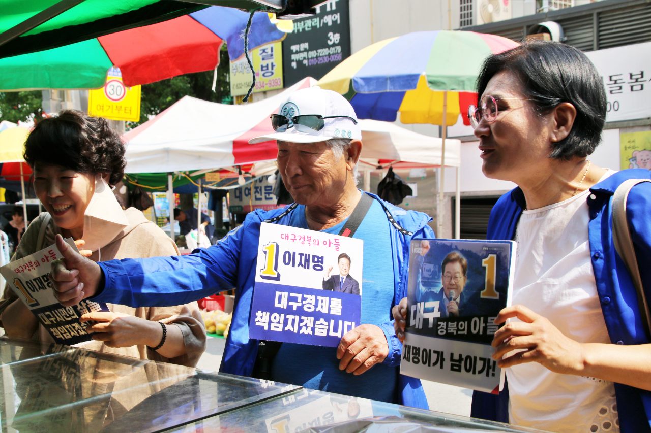 대구가 고향인 재미동포 박영두(76)씨가 대구 달서구 월성 화요시장에서 엄지 척을 하며 이재명 민주당 대선 후보 선거운동을 펼치고 있다. 신혜리, 차우미 두 선거운동원도 함께 상인들에게 지지를 호소하고 있다.(2025.5.27) / 사진.평화뉴스 김영화 기자 