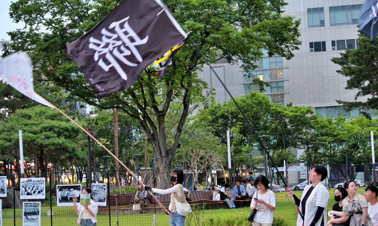 6.10항쟁 기념식에 참석한 시민들이 윤석열 파면 광장에 들고 나왔던 깃발을 흔드는 모습(2025.6.10) / 사진.평화뉴스 정준민 기자