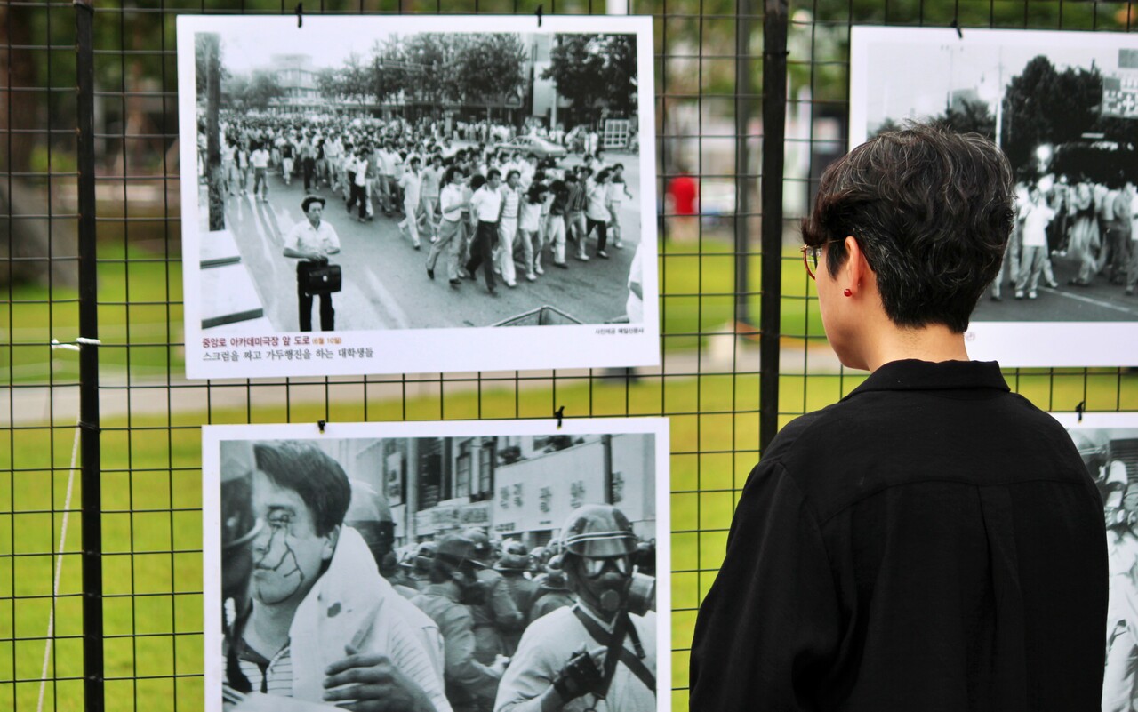정한숙 조국혁신당 대구시당 여성위원장이 기념식 한켠에 설치된 6월 민주항쟁 당시 대구 모습을 담은 사진을 지켜보고 있다.(2025.6.10) / 사진.평화뉴스 정준민 기자