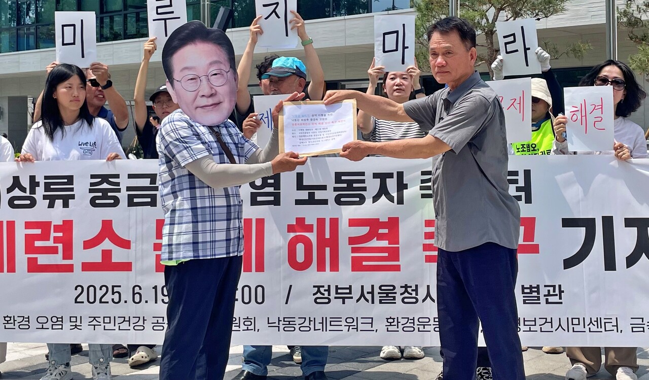 김수동 안동환경운동연합 대표(오른쪽)가 이재명 대통령 탈을 쓴 사람에게 "영풍제련소 문제 해결" 제안서를 전달하고 있다.(2025.6.19) / 사진 제공.안동환경운동연합