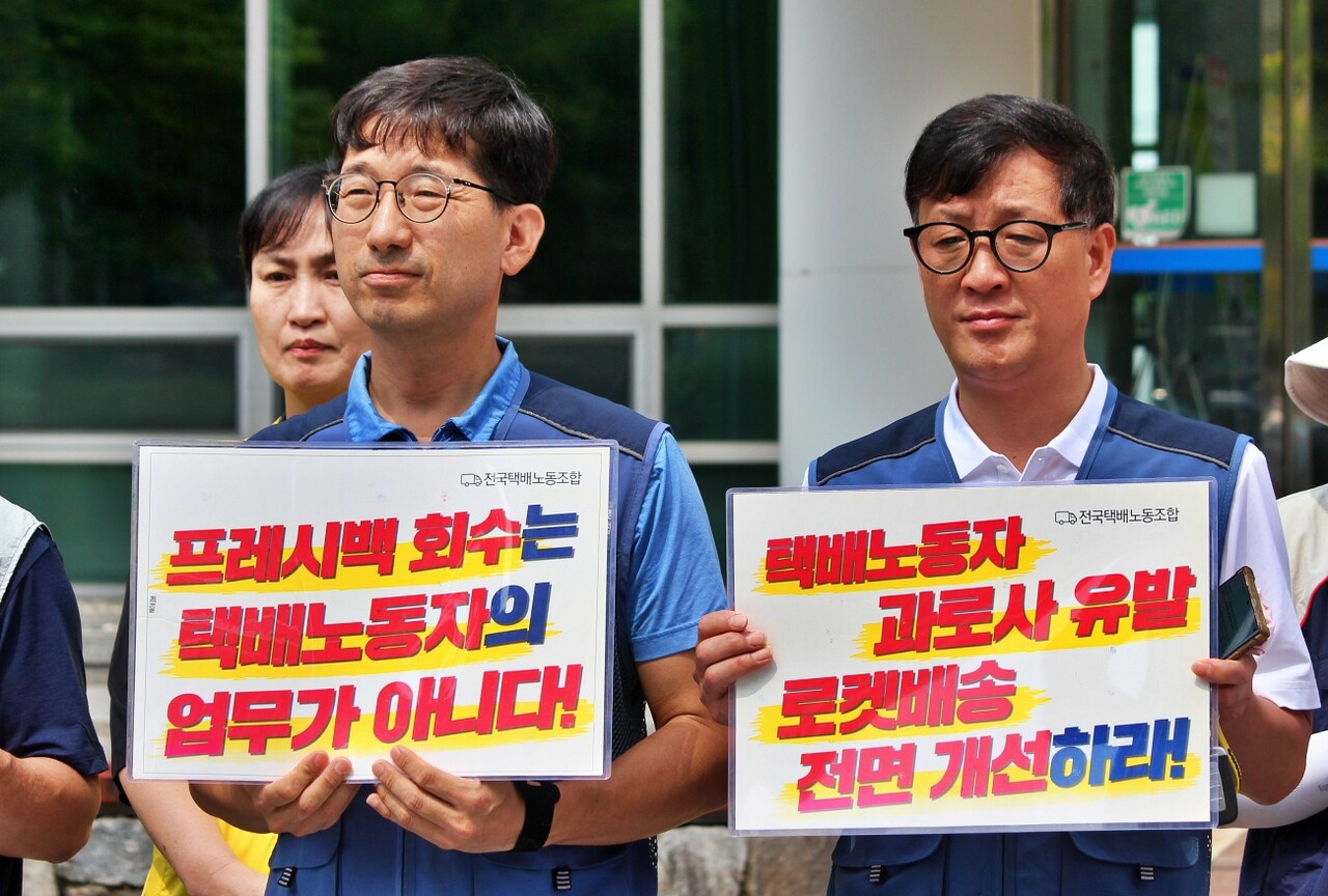 (왼쪽) 정현태 택배노조 대경지부 CJ대구중지회장이 "프레시백 회수는 택배노동자의 업무가 아니다"라고 적힌 피켓을, 박광국 사무부장이 "택배노동자 과로사 유발 로켓배송 전면 개선하라"는 내용의 피켓을 들고 있다.(2025.7.14) / 사진.평화뉴스 정준민 기자