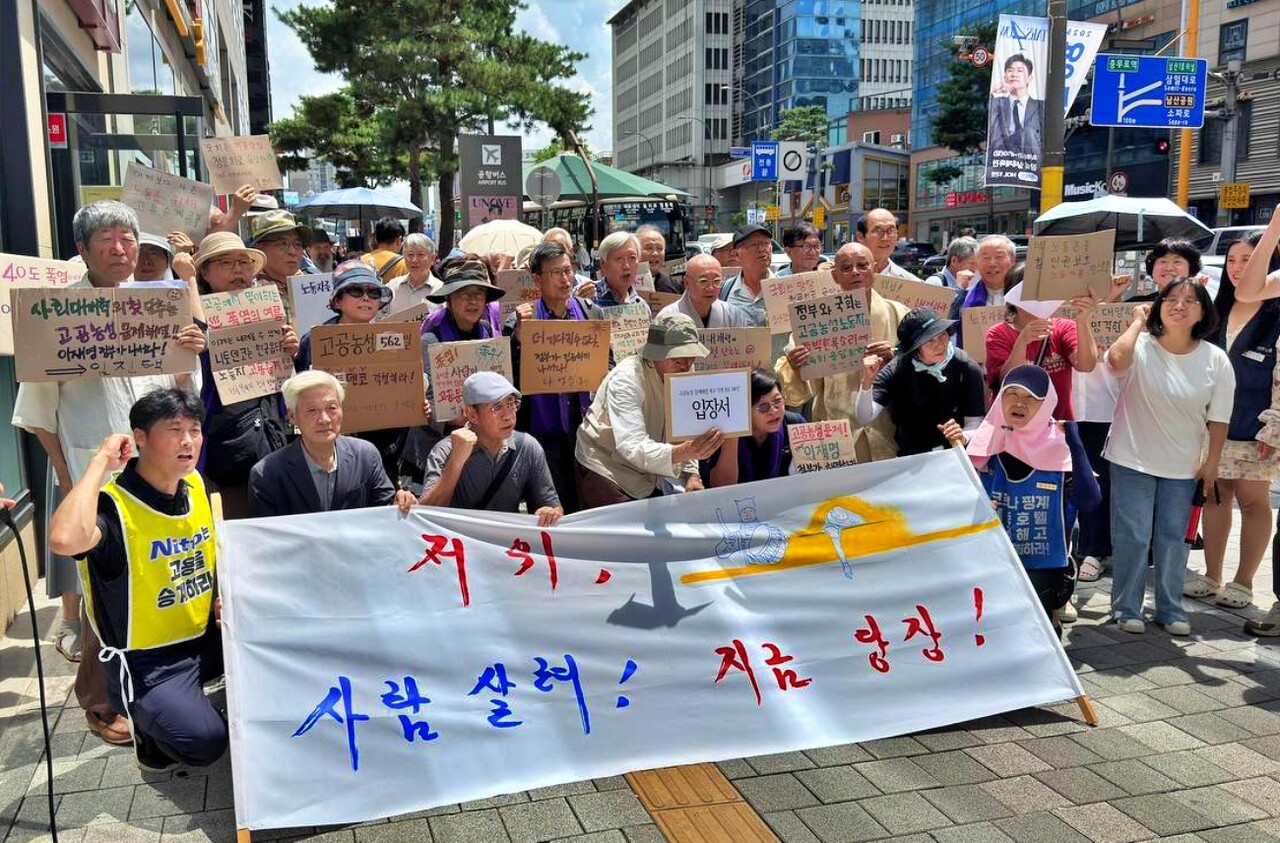 "저 위, 사람 살려. 지금 당장" 이라고 적힌 현수막을 들고 "고공농성 사업장 문제 해결"을 촉구하고 있다.(2025.7.22.서울 명동) / 사진 제공.금속노조 한국옵티칼하이테크지회 