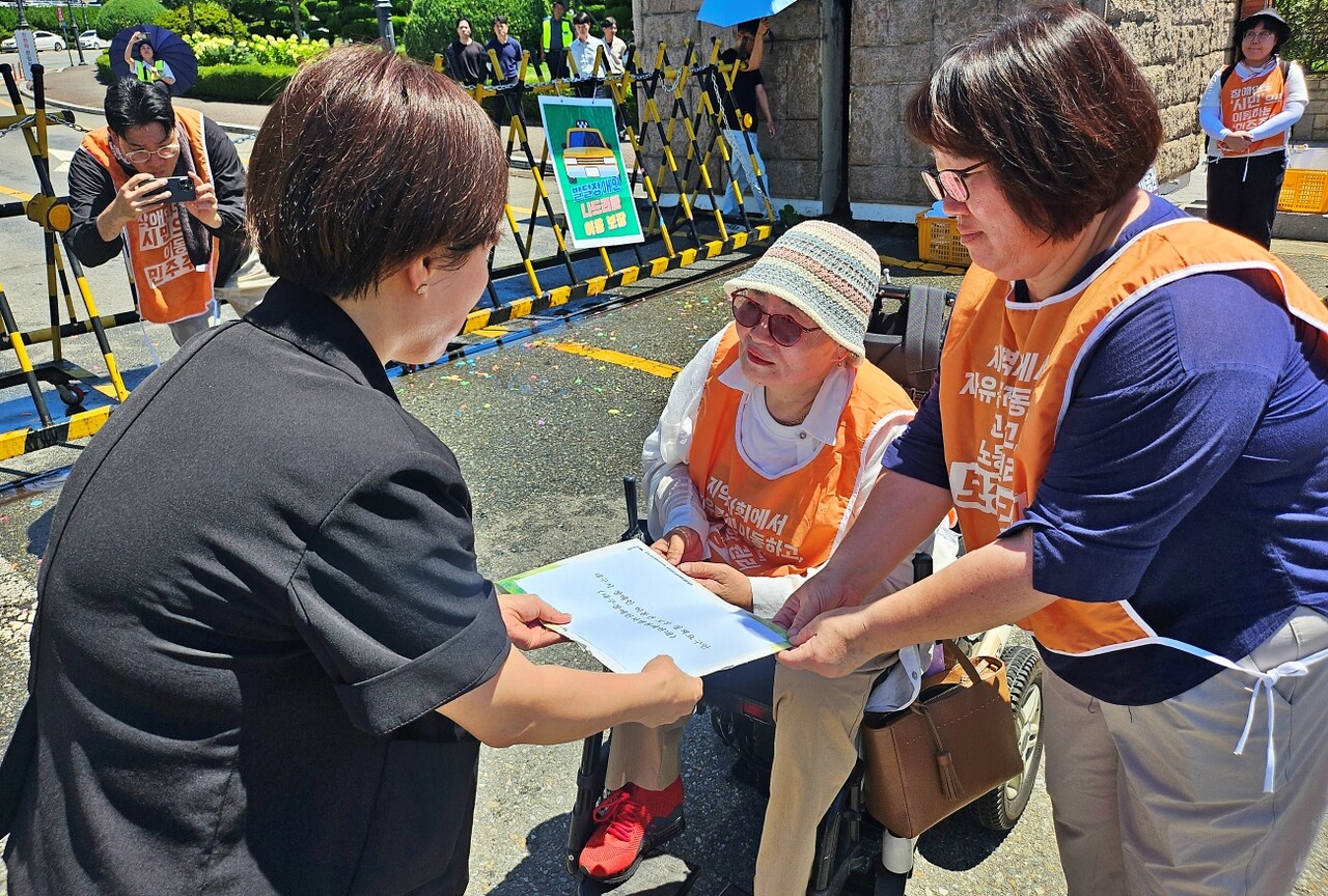박명애 대구장차연 상임공동대표(왼쪽)와 김경숙 전국장애인부모연대 대구지부장(오른쪽)이 대구시 택시물류과 관계자에게 요구안을 전달하고 있다.(2025.7.29) / 사진.평화뉴스 정준민 기자