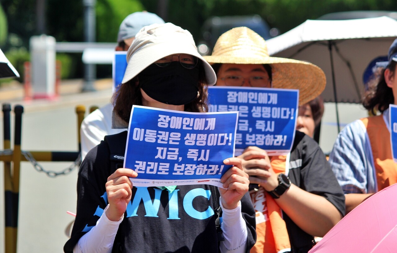 "장애인에게 이동권은 생명이다. 지금 즉시 권리로 보장하라"라고 적힌 종이를 들고 있는 모습(2025.7.29) / 사진.평화뉴스 정준민 기자