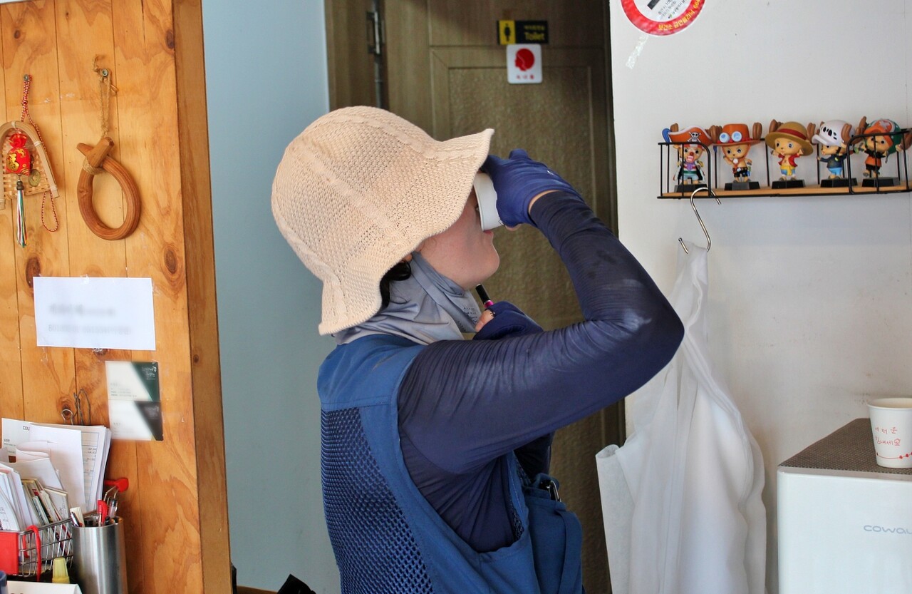 "정수기 물 한잔만 할게요"...이희자씨가 한 식당 건물의 가스 검침을 한 뒤 정수기에서 물을 마시고 있다.(2025.8.4) / 사진.평화뉴스 정준민 기자