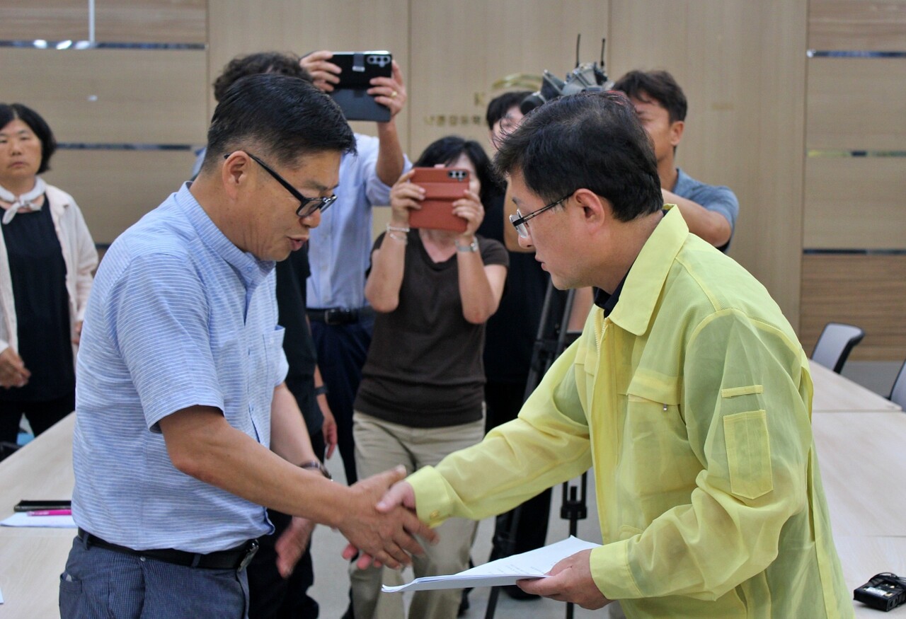 강호열 낙동강네트워크 공동대표(왼쪽)가 김성환 환경부 장관(오른쪽)에게 제안서를 전달하며 악수하고 있다.(2025.8.7) / 사진.평화뉴스 정준민 기자