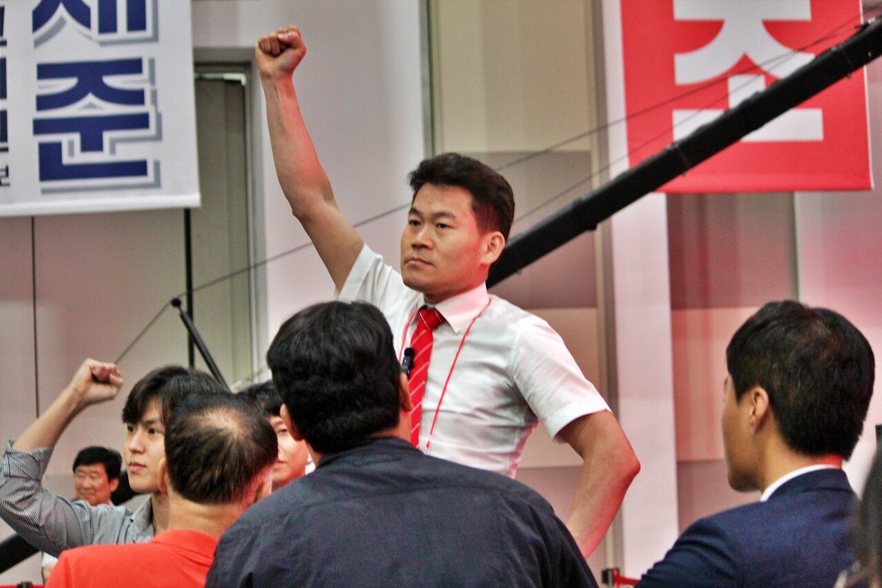 전직 한국사 강사 전한길씨가 합동연설회에서 당대표 후보들의 연설이 이어지는 도중 의자 위에 올라 청중들에게 자신의 팔을 들어올렸다(2025.8.8) / 사진.평화뉴스 정준민 기자