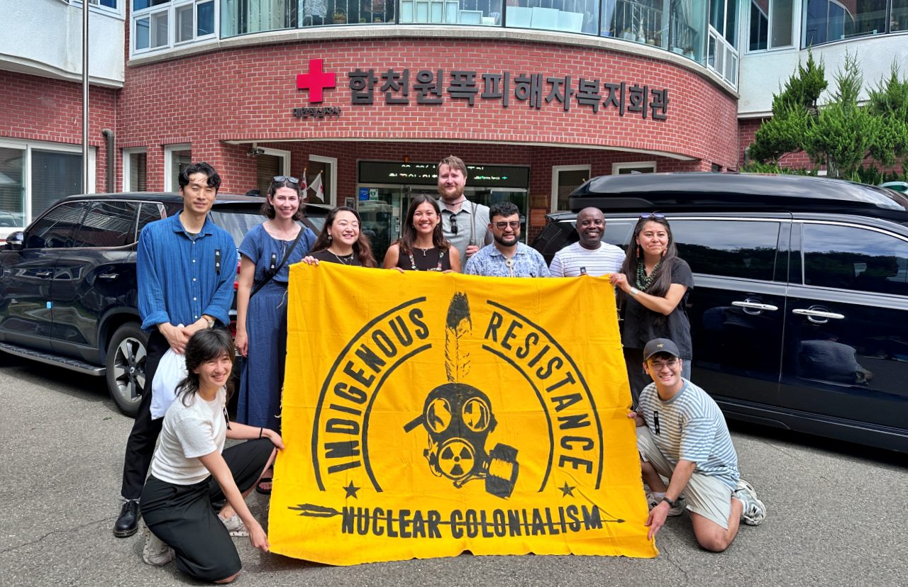 합천원폭피해자복지회관에서 '비핵 평화운동' 깃발을 들고 기념사진을 찍는 사람들(2025.8.6) / 사진.합천비핵평화대회