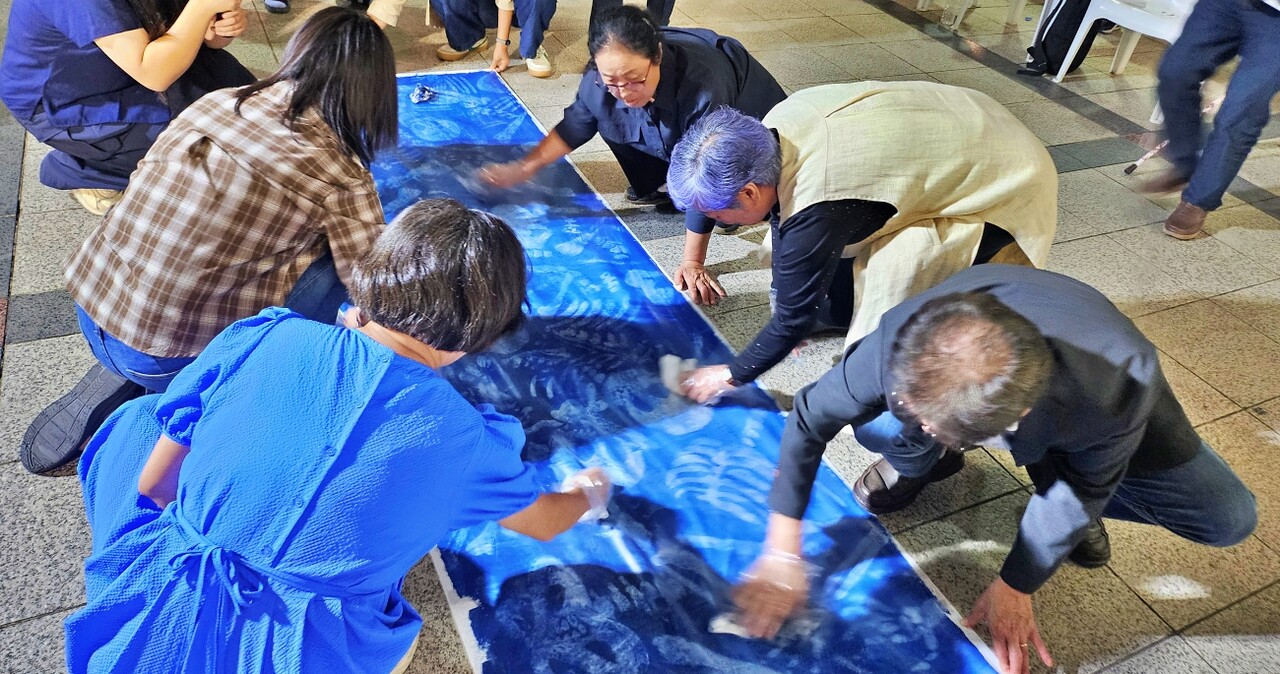 시민들이 천에 색칠된 푸름 물감을 닦아 유골 그림이 나오게 하고 있다.(2025.9.30) / 사진.평화뉴스 정준민 기자