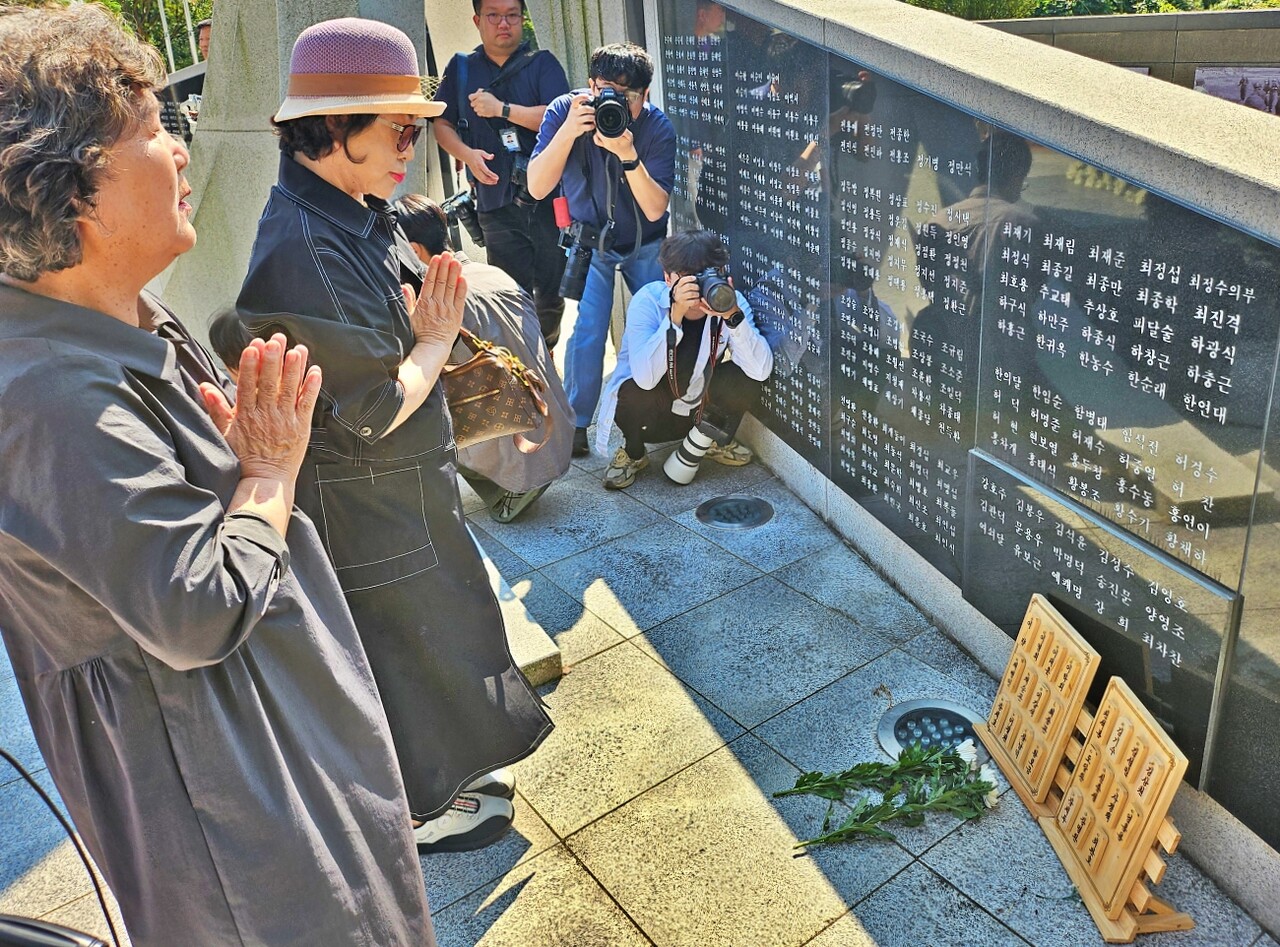10월항쟁과 한국전쟁기 민간인 학살 유족들이 위령탑에 적힌 아버지의 이름 앞에 꽃을 놓으며 기도하고 있다.(2025.10.1) / 사진.평화뉴스 정준민 기자