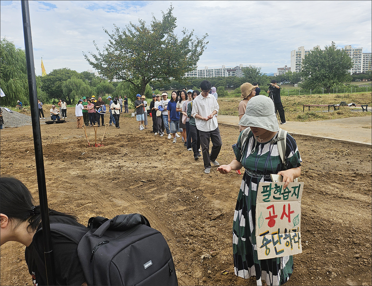 2025년 9월 5일, 팔현습지 보도교 시공업체가 세륜시설 설치를 위해 풀밭을 밀어내자 시민들이 밀린 풀밭을 돌며 "공사 중단"을 촉구하고 있다.(2025.9.8) / 사진. 평화뉴스 정준민 기자