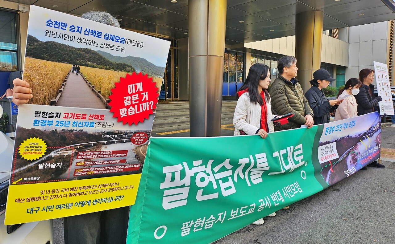 순천만 습지 산책로와 팔현습지 보도교를 비교한 사진이 담긴 피켓을 들고 있다.(2025.11.11) / 사진.평화뉴스 정준민 기자